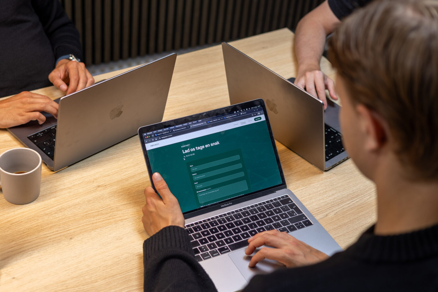 Kollegaer arbejder på laptops ved mødebordet